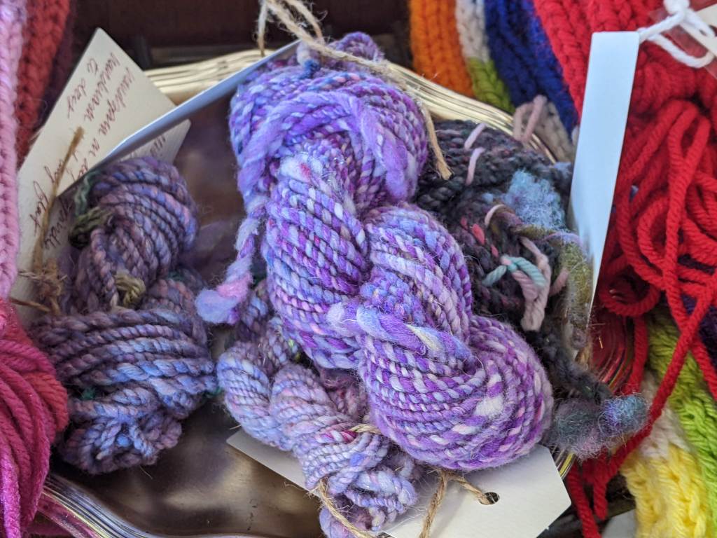 Small skeins of yarn in purples and blues with cardboard tags
